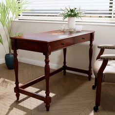 a wooden desk sitting next to a chair near a window