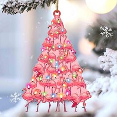 a pink christmas tree ornament with flamingos hanging from it's sides