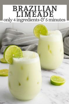 two glasses filled with white liquid and limes