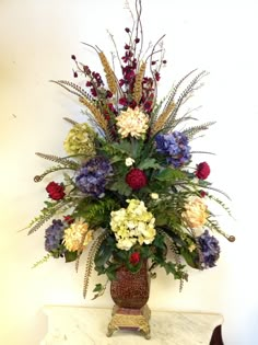 a vase filled with lots of flowers on top of a white marble counter next to a wall