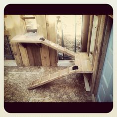 a wooden shelf sitting on top of a floor next to a wall with a mirror in it