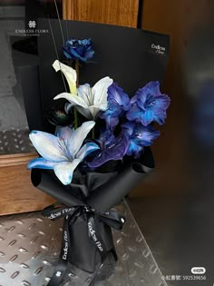 blue and white flowers are wrapped in black paper