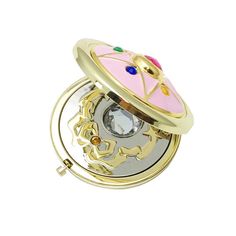 a gold and pink clock with an ornate design on the front, sitting on a white surface