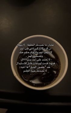 a cup filled with liquid sitting on top of a black counter next to an arabic quote