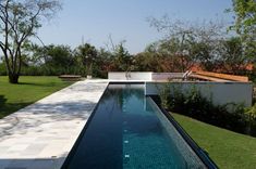 an empty swimming pool in the middle of a lush green yard