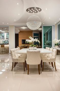 a large dining room with white chairs and a chandelier hanging from the ceiling