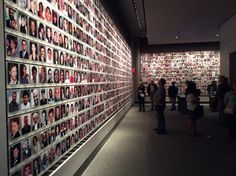 people are standing in front of a wall with many pictures on it and one person is looking at the camera