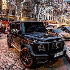 a black mercedes g - class parked on the street