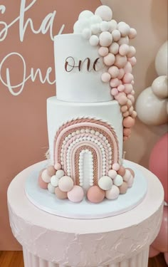 a white and pink cake with balloons on top