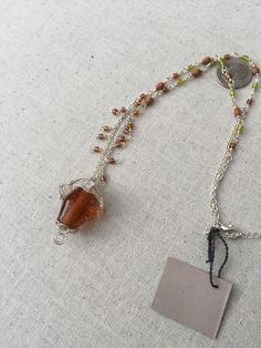 a necklace with beads and a tag on the end that has a chain attached to it