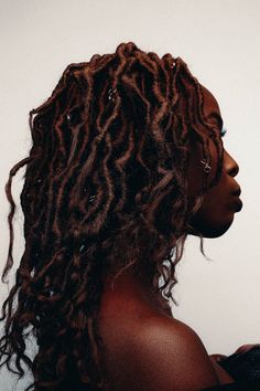 a woman with long curly hair standing in front of a white wall