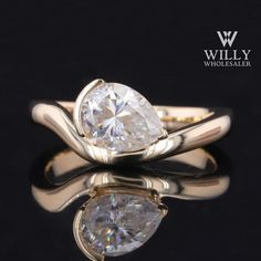 an engagement ring with two pear shaped diamonds on the side, set in 18k yellow gold