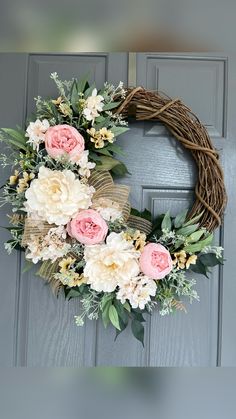 a wreath with pink and white flowers hanging on a door