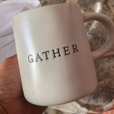 a hand holding a coffee mug with the word gather on it