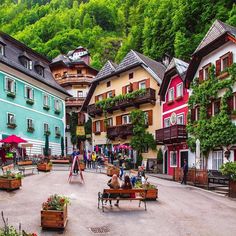 people are sitting on benches in the middle of an open area with many colorful buildings