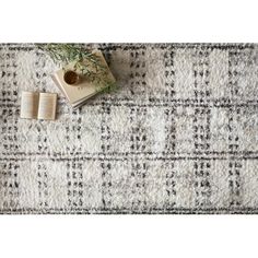 an open book and some plants on top of a white rug with black and gray checkered pattern