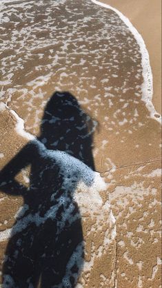 a shadow of a person standing on the beach