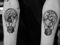 black and white photo of two light bulbs with human heart inside them on both forearms