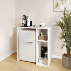 a small white cabinet with drawers in the corner next to a potted palm tree