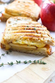 a grilled cheese sandwich with an apple in the background