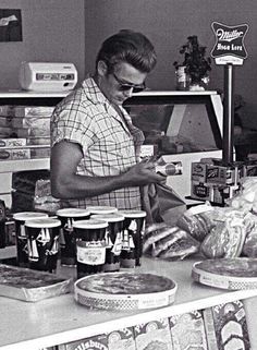 an old black and white photo of a woman making pizzas in a store kitchen