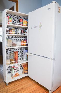 an open refrigerator with food in it on top of a wooden floor next to a window