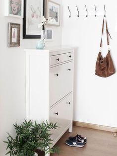 a white dresser sitting next to a wall with pictures hanging on it's sides