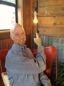 a man sitting in a red chair holding up a lightbulb above his head