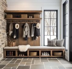 a coat rack with shoes and coats hanging on the wall next to a bench in front of a window