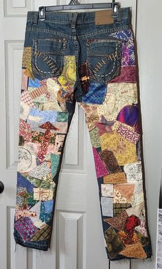 a pair of jeans with patchwork on them hanging from a door