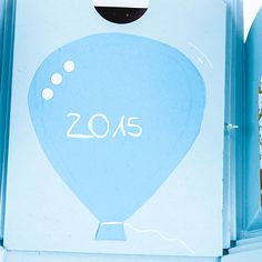 an open box with a blue hot air balloon on the front and white lettering that says 2013