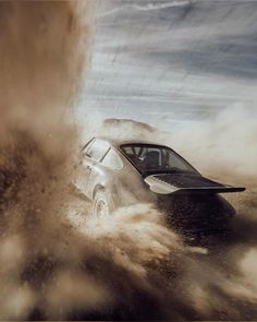 a car is driving through the sand with it's wheels in the air and splashing around