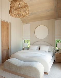 a large bed sitting in a bedroom next to a wooden ceiling mounted light above it