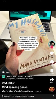 someone is holding up a book in front of their laptop computer with the caption'my husband, mad venture'written on it