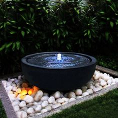 a water fountain surrounded by rocks in a garden