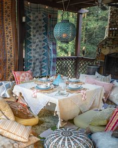 a table with plates and cups on it in the middle of a room filled with pillows