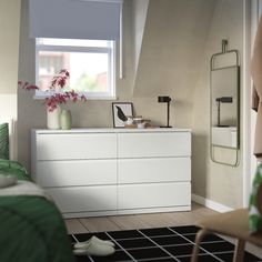 a white dresser sitting in a bedroom next to a window with a plant on top