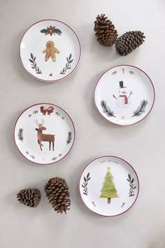 four plates decorated with christmas designs and pine cones