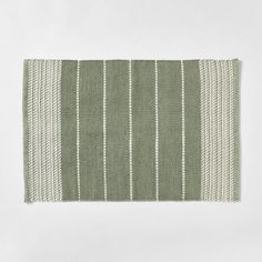 a green and white striped rug on a white surface