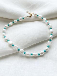 Freshwater pearl necklace with turquoise seed beadsEach piece is designed and handmade in Brooklyn. After visiting the Notre Maison orphanage in 2015, I fell in love with the children and knew I wanted to help sponsor them. That's what started this shop. Every purchase helps us sponsor 5 children at the orphanage that we follow up with and visit over the summers. Join our Ubuntu family so that together we can be the village that takes care of these children.SIZINGNecklace is 16" long with 2" adj Bohemian Turquoise Pearl Necklace With Colorful Beads, Bohemian Beaded Turquoise Pearl Necklace, Bohemian Turquoise Beaded Pearl Necklace, Turquoise Pearl Necklace With Colorful Beads, Turquoise Pearl Necklace With Colorful Beads As Gift, Turquoise Round Beads Pearl Necklace For Beach, Turquoise Pearl Necklace With Round Beads For Beach, Handmade Turquoise Pearl Necklace For Beach, Turquoise Beaded Pearl Necklace