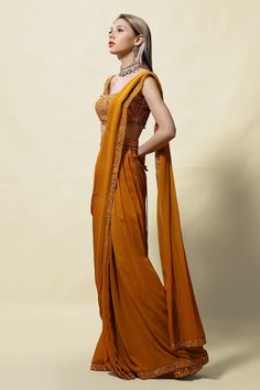 Mustard pre-draped saree with mirror embroidery on the border. Comes with sleeveless blouse and belt.
Component: 3
Pattern: Embroidery
Type Of Work: Mirror, Cutdana, Beads and Thread
Neckline: Scoop
Sleeve Type: Sleeveless
Fabric: Blouse: Silk and Saree: Georgette; Lining: Shantoon
Color: Yellow
Other Details: 
Pre-pleated pallu
Blouse with bead drops
Closure: Side zip
Occasion: Sangeet - Aza Fashions Traditional Fitted Dupatta With Draped Sleeves, Yellow Pre-draped Saree For Wedding, Fitted Dupatta With Draped Sleeves For Wedding, Traditional Draped Sleeves Choli For Wedding, Wedding Dupatta With Draped Sleeves, Wedding Draped Art Silk Dupatta, Wedding Art Silk Draped Dupatta, Mirror Blouse, Yellow Mirror