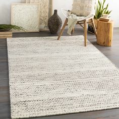 a white rug in the middle of a room with plants and pictures on the wall