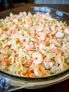 a glass bowl filled with pasta and shrimp