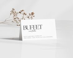 a business card sitting on top of a table next to a flower vase with dried flowers in it