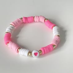 a pink and white beaded bracelet with gold accents on a white tablecloth background