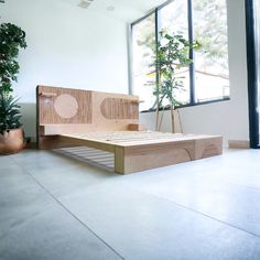 a bed sitting on top of a white floor next to a plant in a room