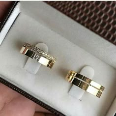 two gold rings are in a box on the table, one is white and the other is black