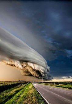 a large cloud is in the sky over a road