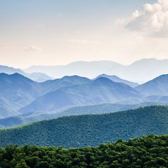 the mountains are covered in green trees and blue sky