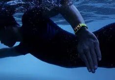 a man swimming in the water with his hand on his chest and wristband around his neck